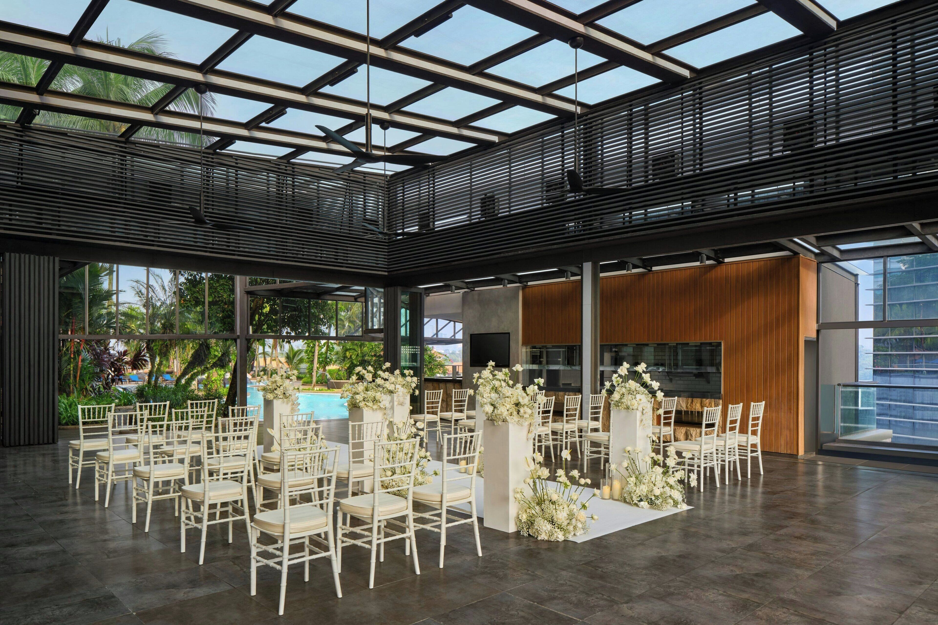 A spacious indoor area with a high ceiling, modern furniture, and a large window overlooking greenery.