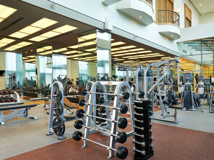 Ein Fitnessstudio mit verschiedenen Trainingsgeräten, darunter Kraftgeräte und Kurzhanteln.