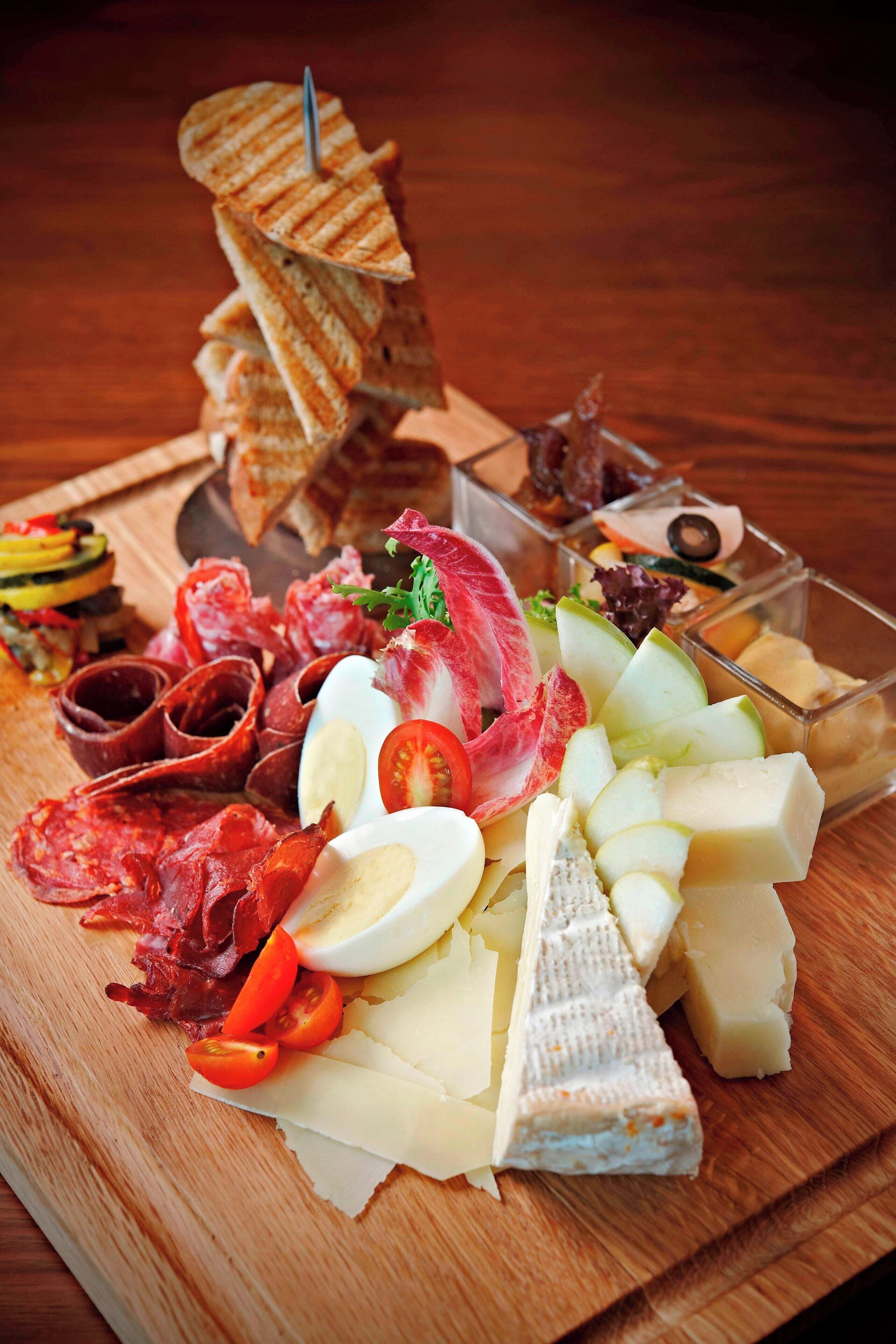 A charcuterie board with various meats, cheeses, and fruits.