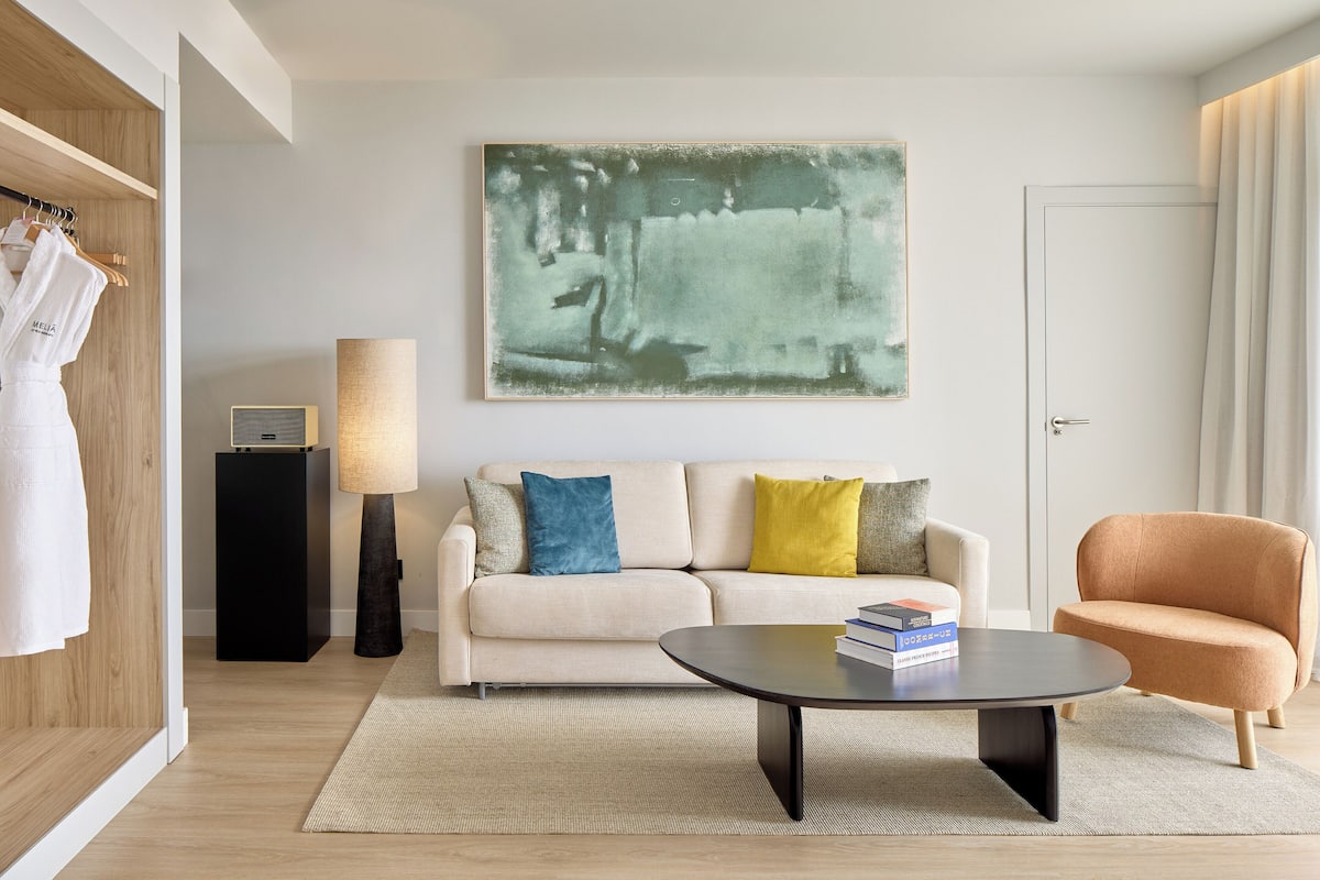 Ein modernes Wohnzimmer mit einer Couch, einem Couchtisch, einer Lampe und einem Gemälde an der Wand.