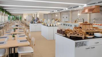 A modern dining area with long tables, chairs, and a buffet with various food items.