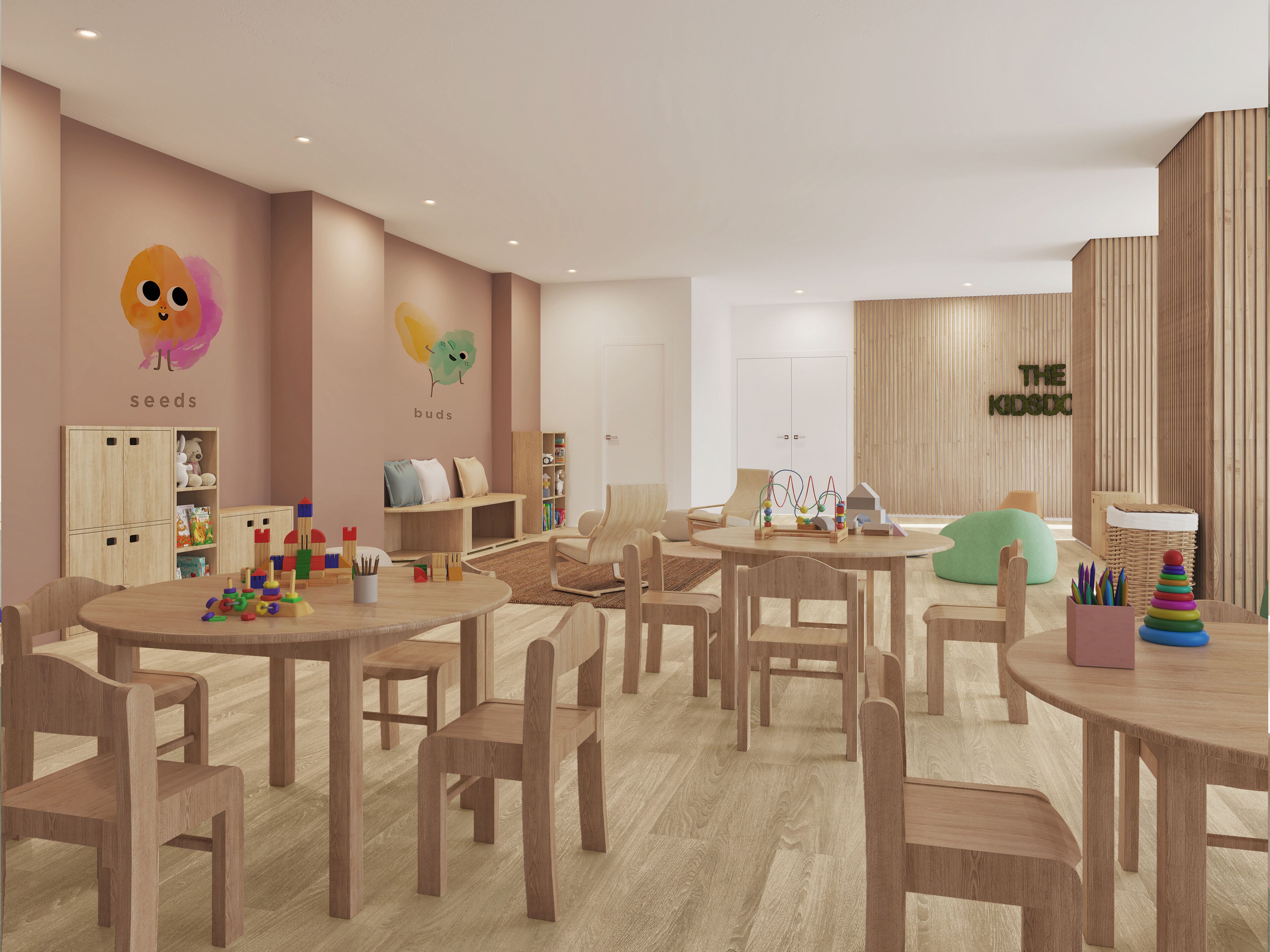 Una sala de juegos para niños con muebles de madera, una pared con decoración lúdica y una puerta visible con la leyenda 'THE KIDSOC'.