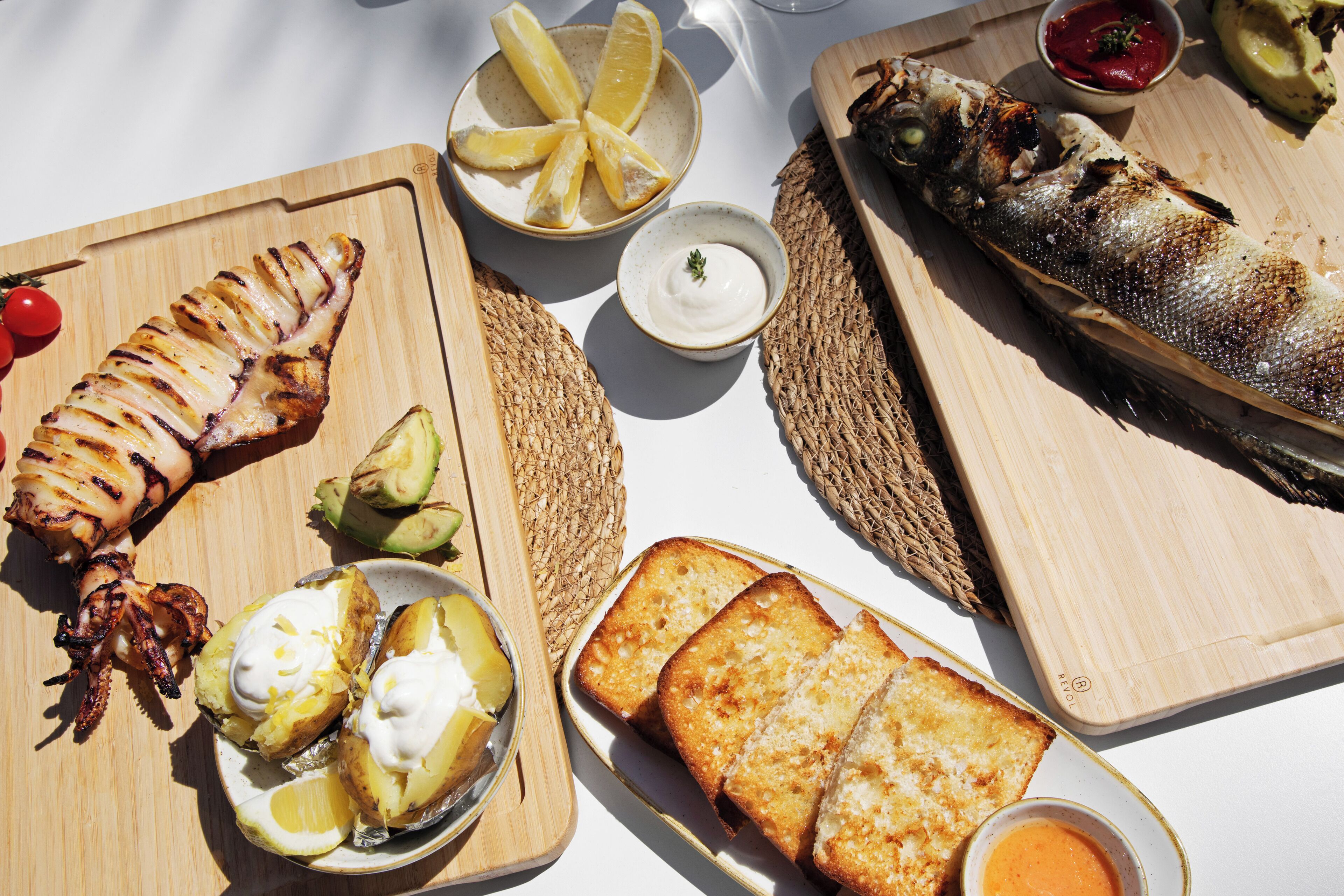 Une variété de fruits de mer grillés et de pain, présentés sur des planches en bois.