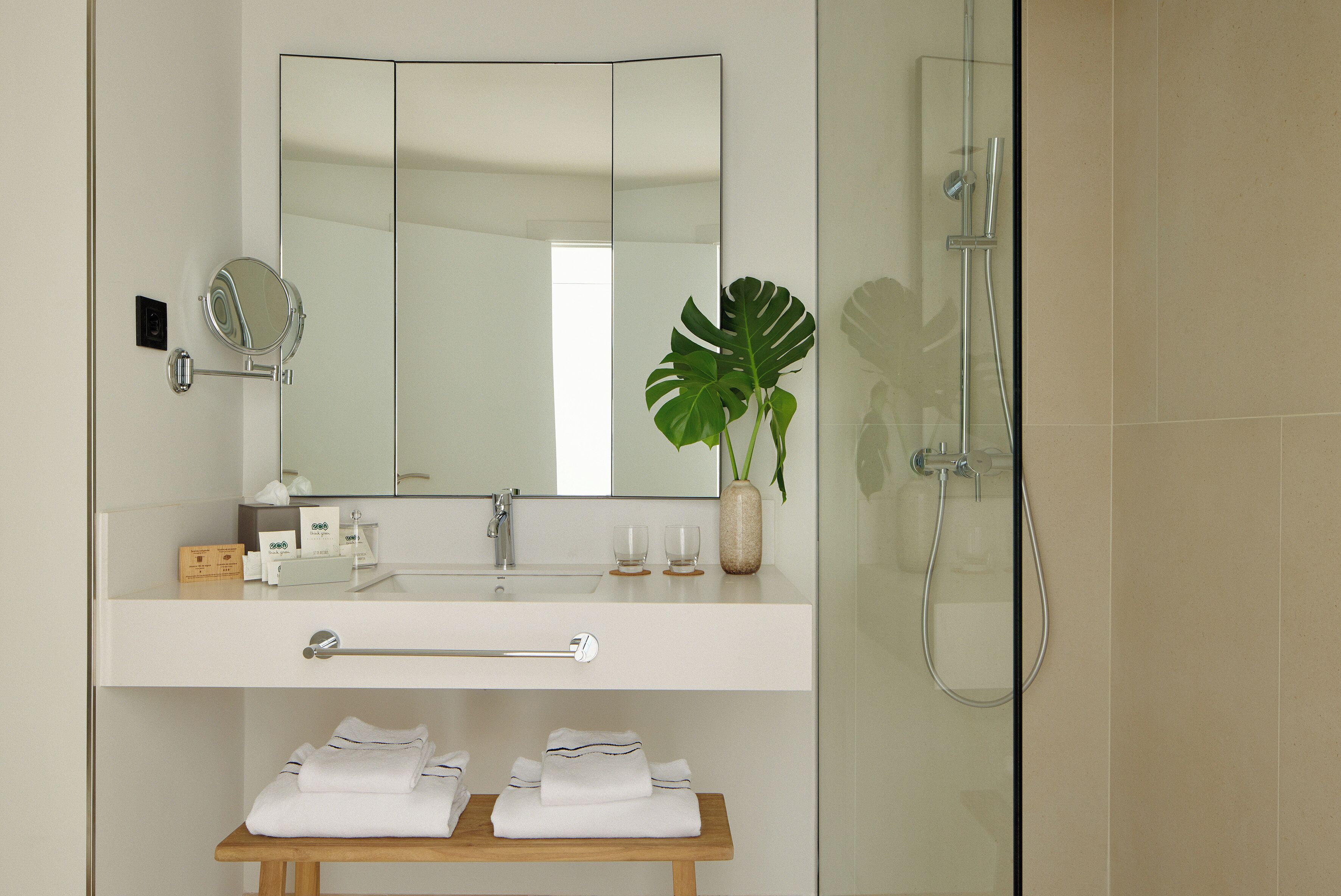 Ein modernes Badezimmer mit großem Spiegel, Waschbecken, Handtuchhalter und Dusche.