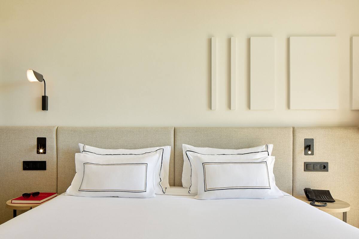 Ein Hotelzimmer mit Bett, Nachttischen, einer Lampe und Wandleuchten.