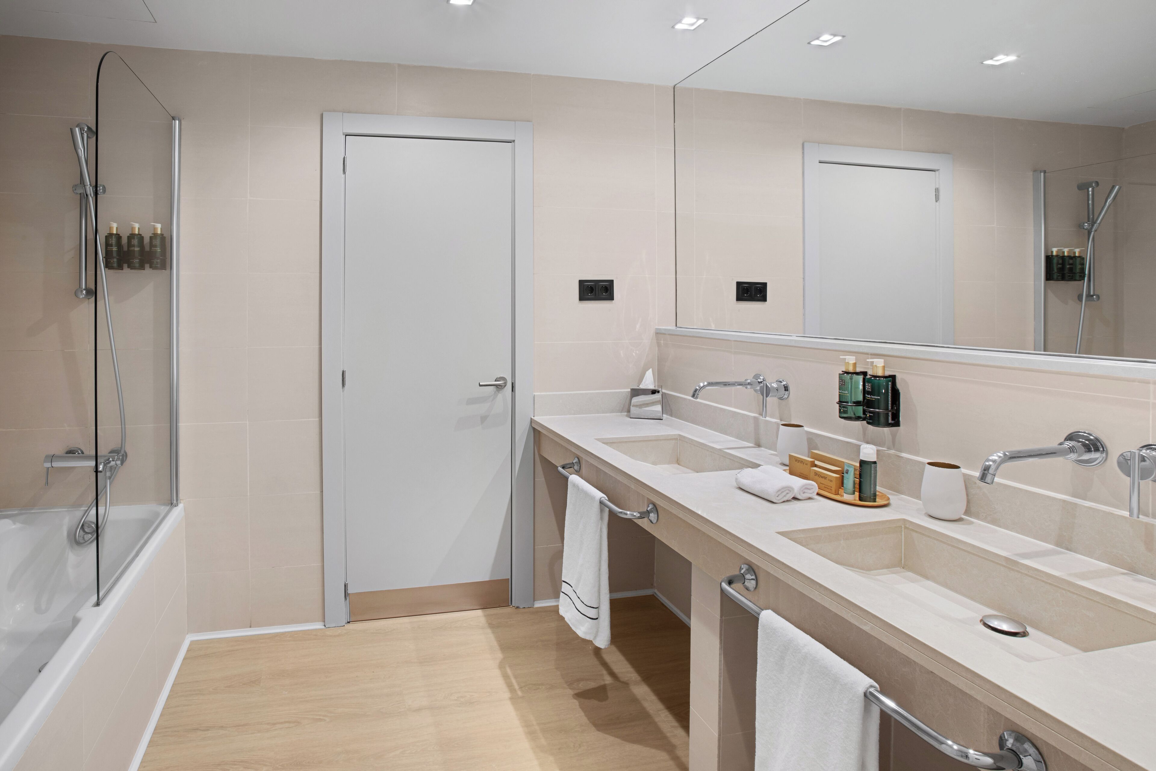 Un bagno moderno con vasca, due lavandini, uno specchio grande e cabina doccia.
