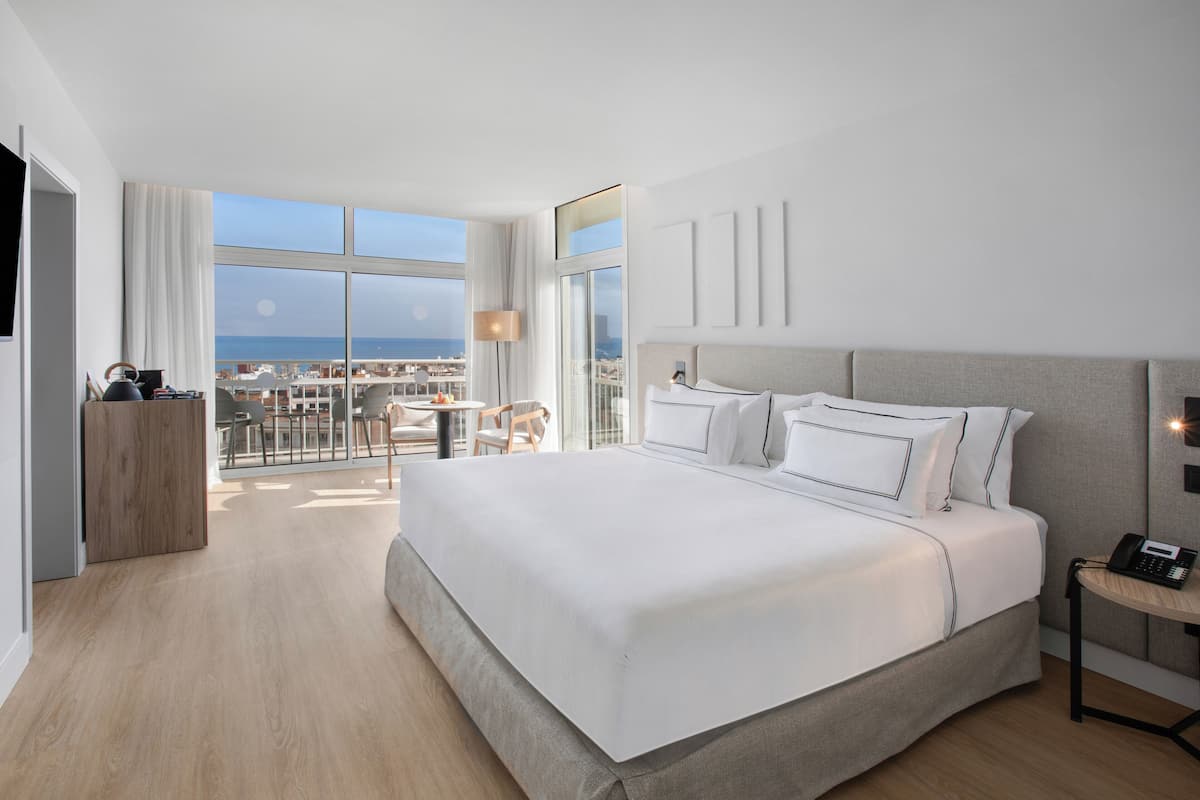 Ein modernes Hotelzimmer mit einem großen Bett, einem Schreibtisch und Blick auf die Stadt.