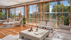A modern living room with a large window, wooden blinds, a coffee table, and comfortable seating. - Melia Lloret de Mar (Lloret de Mar)