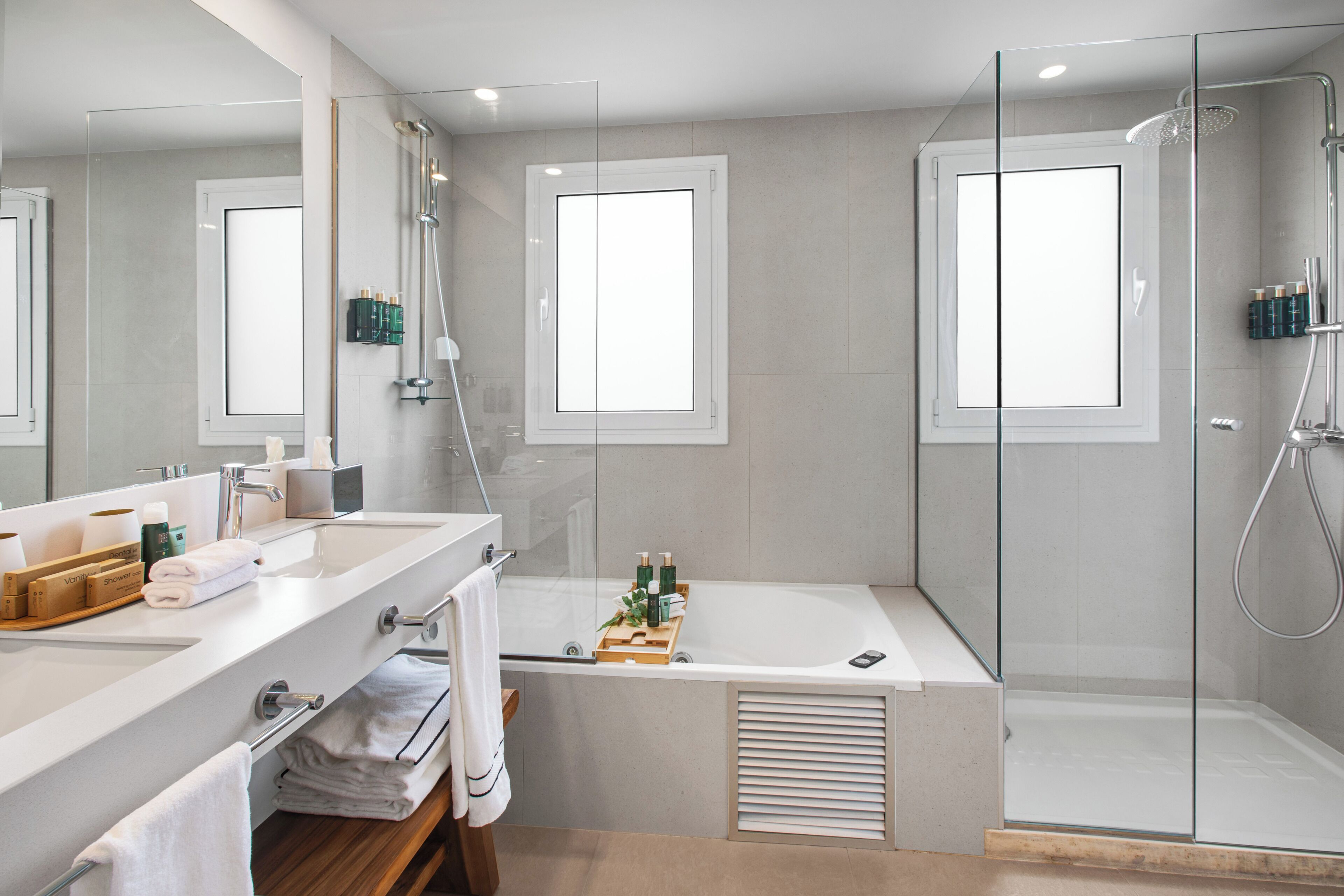 A modern bathroom with a large mirror, a bathtub, and a glass-enclosed shower.