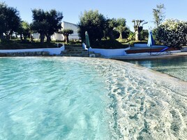 Una piscina al aire libre, sombrillas, sillones reclinables de piscina