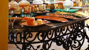 A dining table with glassware and food, set in a room with yellow walls and an arched doorway. - Hotel Capela das Artes (Silves)