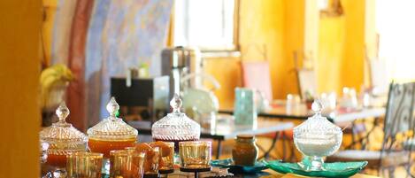 Una mesa de comedor con cristalería y comida, en una habitación con paredes amarillas y un arco.