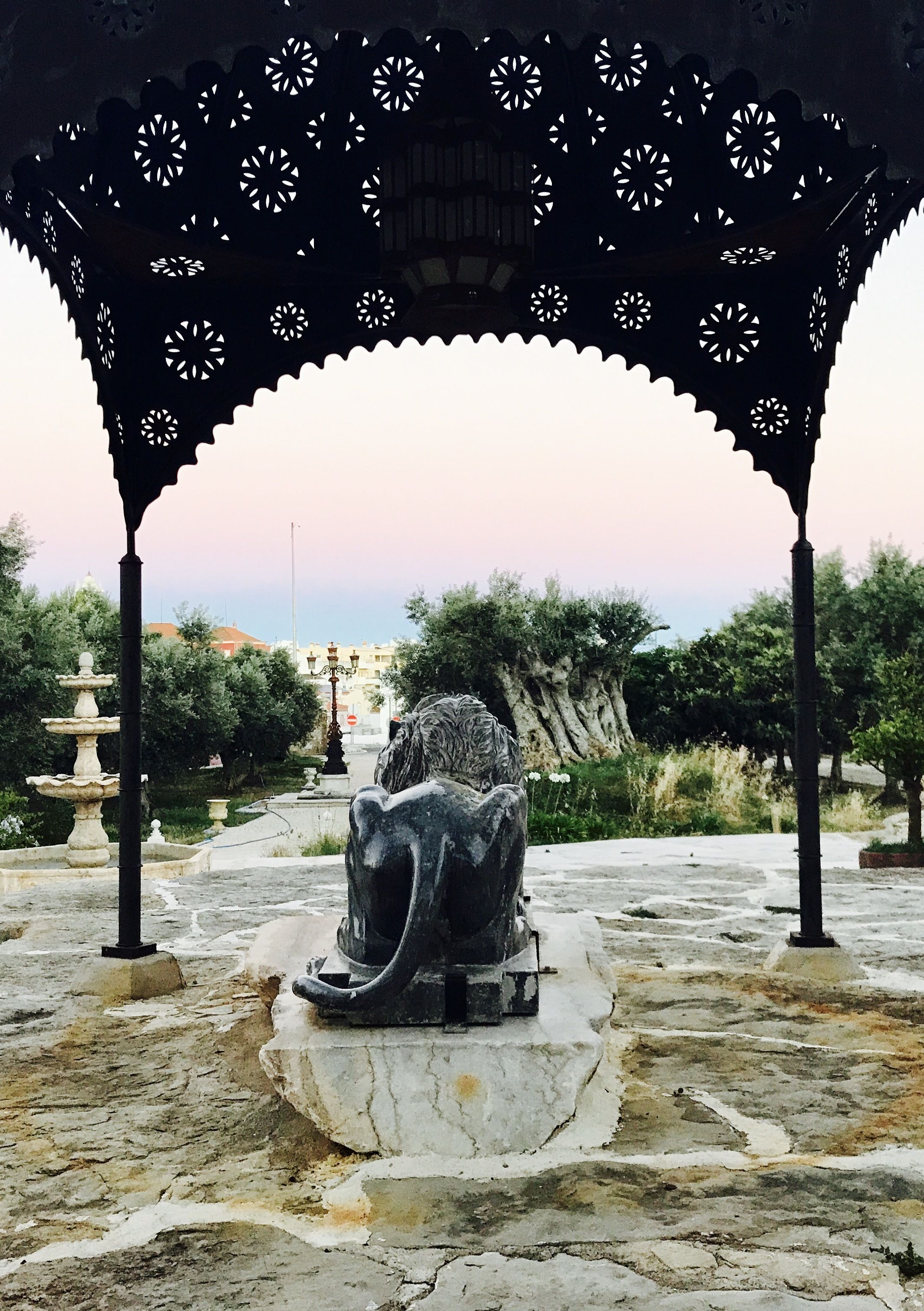 Un vialetto in pietra conduce a un gazebo con decorazioni intagliate.