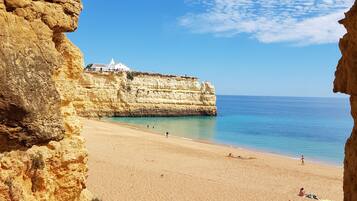 Enjoy breathtaking views of the coastline through this natural rock archway, leading to a serene sandy beach.