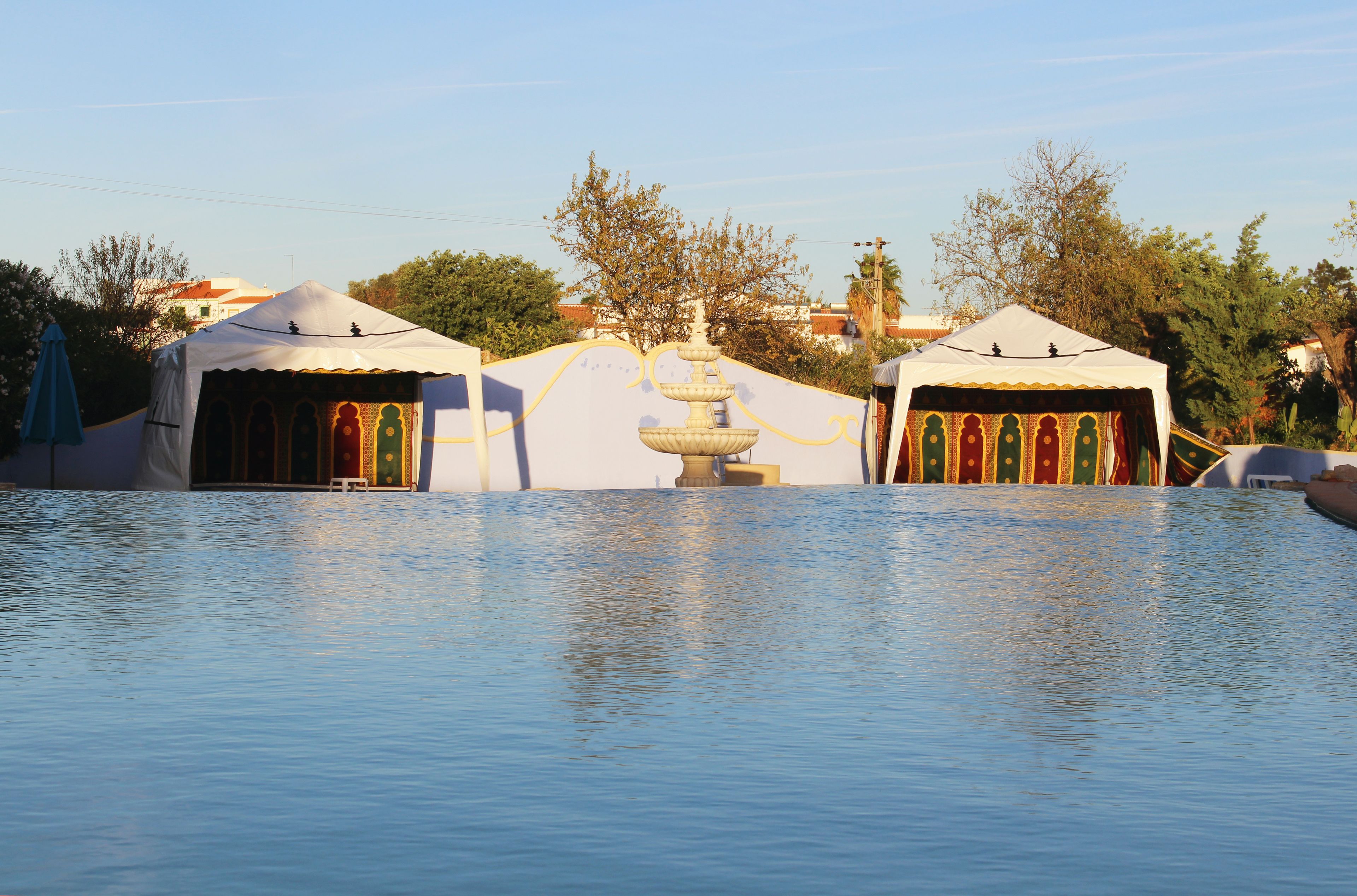 Una piscina al aire libre, sombrillas, sillones reclinables de piscina
