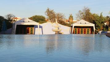 Una piscina al aire libre, sombrillas, sillones reclinables de piscina