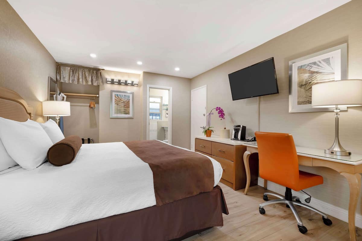 Habitación de hotel con cama, escritorio, silla, televisión y obras de arte.
