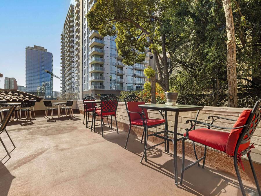 An outdoor patio with tables and chairs, surrounded by trees and buildings.