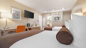 Una camera d'albergo con un letto grande, una scrivania con lampada, una televisione e una sedia.
