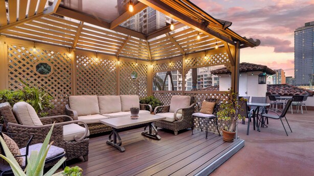 Patio esterno con mobili in vimini, una pergola in legno e piante in vaso.