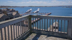 A wooden deck overlooking a calm body of water with boats and buildings in the background.
