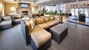 A spacious lobby with a large beige sectional sofa, a stone fireplace, and a flat-screen TV mounted on the wall. - Club Wyndham Long Wharf (Newport)