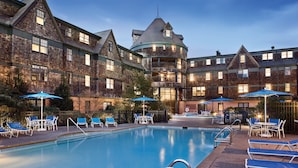 A swimming pool with lounge chairs and umbrellas, surrounded by a brick building with multiple windows and balconies. - Club Wyndham Long Wharf (Newport)