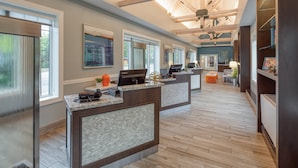 A reception area with a modern design, featuring a reception desk, a seating area, and a view of the outdoors through large windows. - Club Wyndham Long Wharf (Newport)