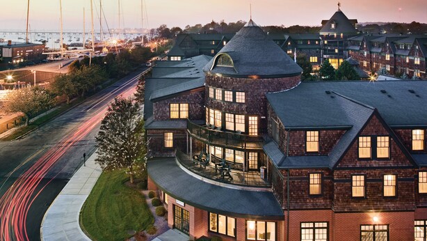 A large, multi-story building with a curved roof and multiple windows, situated near a waterfront with sailboats. - Club Wyndham Long Wharf (Newport)
