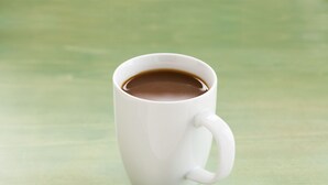 A white mug with a handle on a green surface. - The Chelsean New York (New York)