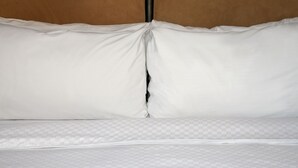 A neatly made bed with white bedding and a checkered mattress cover. - The Chelsean New York (New York)