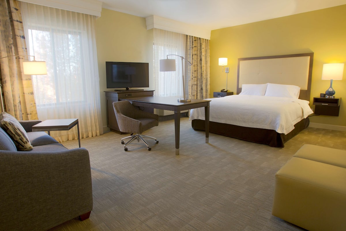 Een hotelkamer met een bed, een bureau, een stoel, een televisie en een lamp.