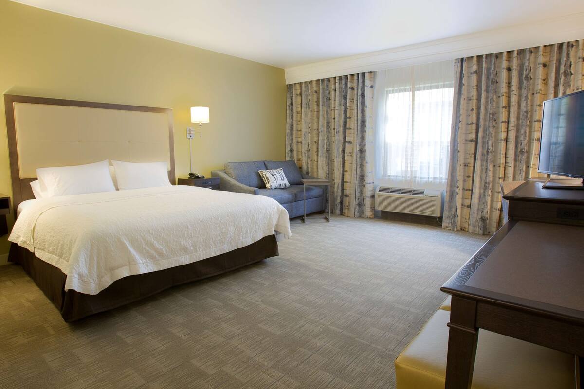 Een hotelkamer met een groot bed, een bureau, een stoel en een televisie.