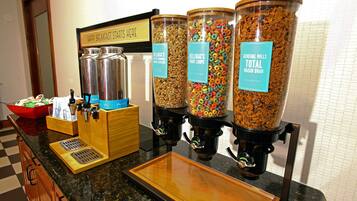 Una estación para el desayuno con dispensadores de Kellogg's Total Raisin Bran, Kellogg's Fruity Pebbles y Kellogg's Mini Corn Flakes.