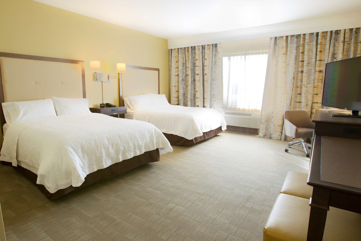 Een hotelkamer met twee bedden, een bureau, een stoel en een televisie.