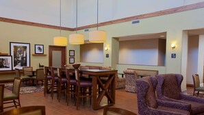 A hotel lobby with a dining area, seating, and a large screen. - Hampton Inn & Suites Boise/Nampa at the Idaho Center (Nampa)