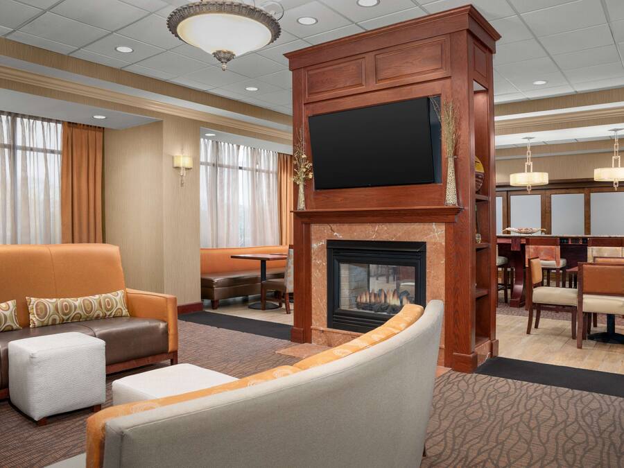 Un hall de hotel con chimenea, zona de estar y televisor montado en una pared de madera.