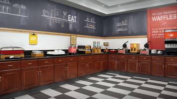 Una cocina con armarios de madera, piso a cuadros blanco y negro, y paredes de pizarra con ilustraciones de comida.