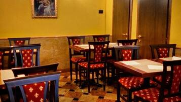 Un restaurant avec des tables et des chaises en bois, un sol à carreaux et un tableau accroché au mur.