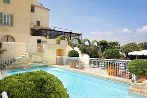 A swimming pool with a white railing, surrounded by greenery and a building with a balcony. - Maison Bérard – hôtel restaurant spa (La Cadiere-d'Azur)
