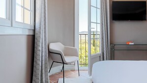 Une chambre d’hôtel moderne équipée d’un lit, d’une chaise, d’une télévision et d’un balcon avec vue.