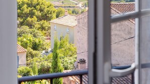 Une vue depuis une fenêtre donnant sur un vignoble avec des terrasses et un bâtiment dont le toit est recouvert de tuiles.
