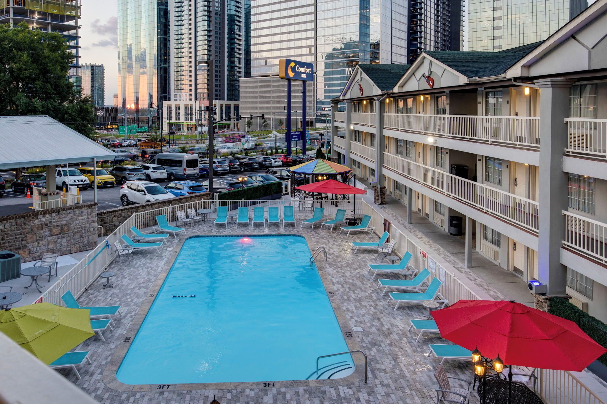 A hotel with a rooftop pool, lounge chairs, and a view of the city skyline.