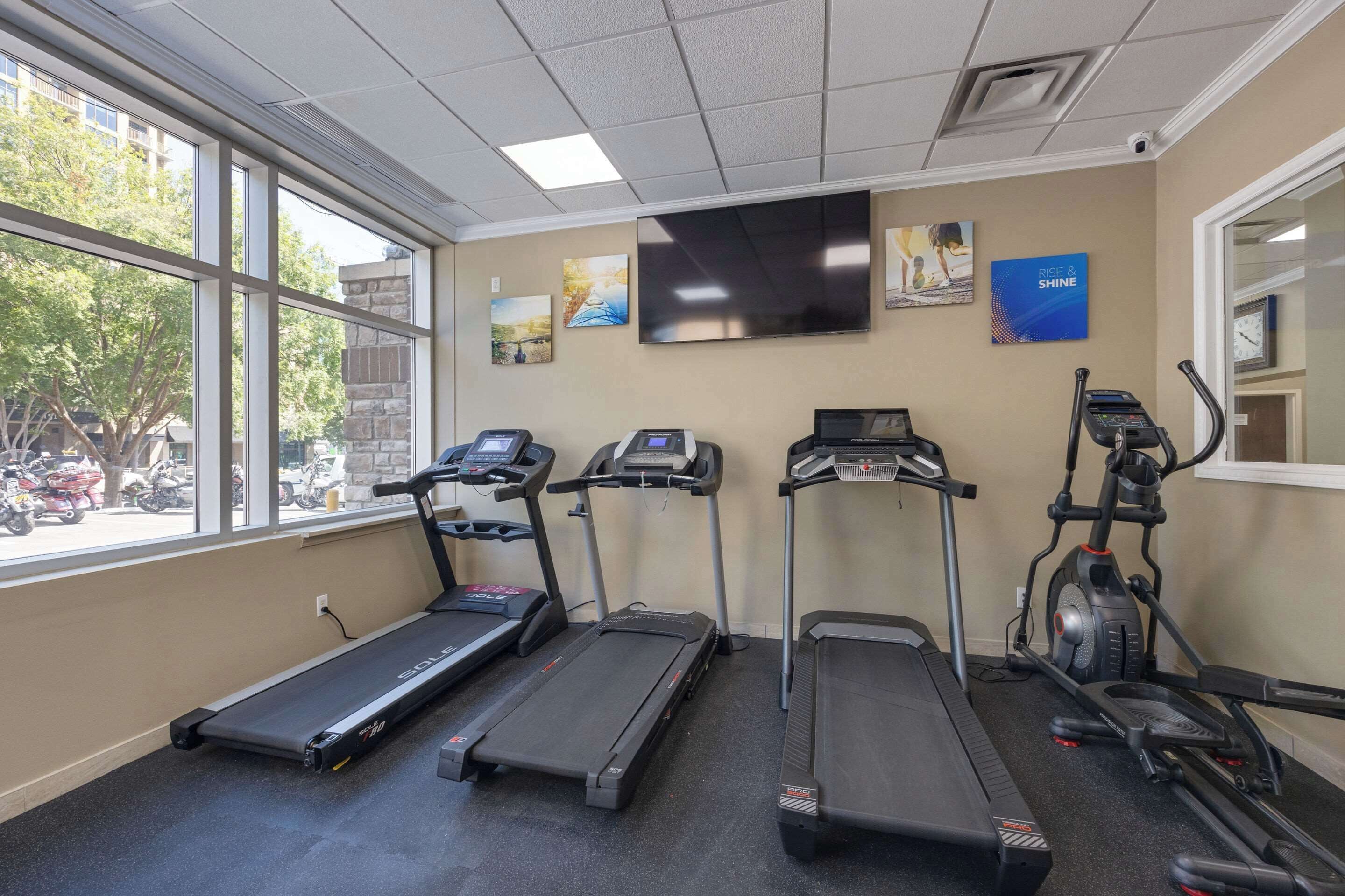 Une salle de sport équipée de tapis de course, d’un vélo elliptique et d’un vélo d’appartement.