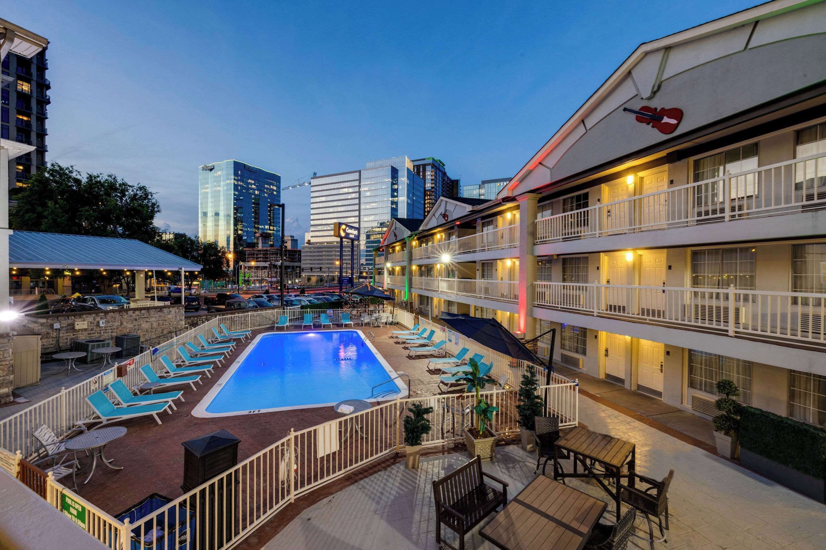 A rooftop pool area with lounge chairs and a swimming pool, surrounded by hotel buildings.