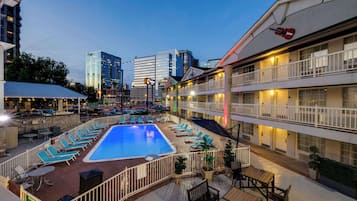 A rooftop pool area with lounge chairs and a swimming pool, surrounded by hotel buildings.