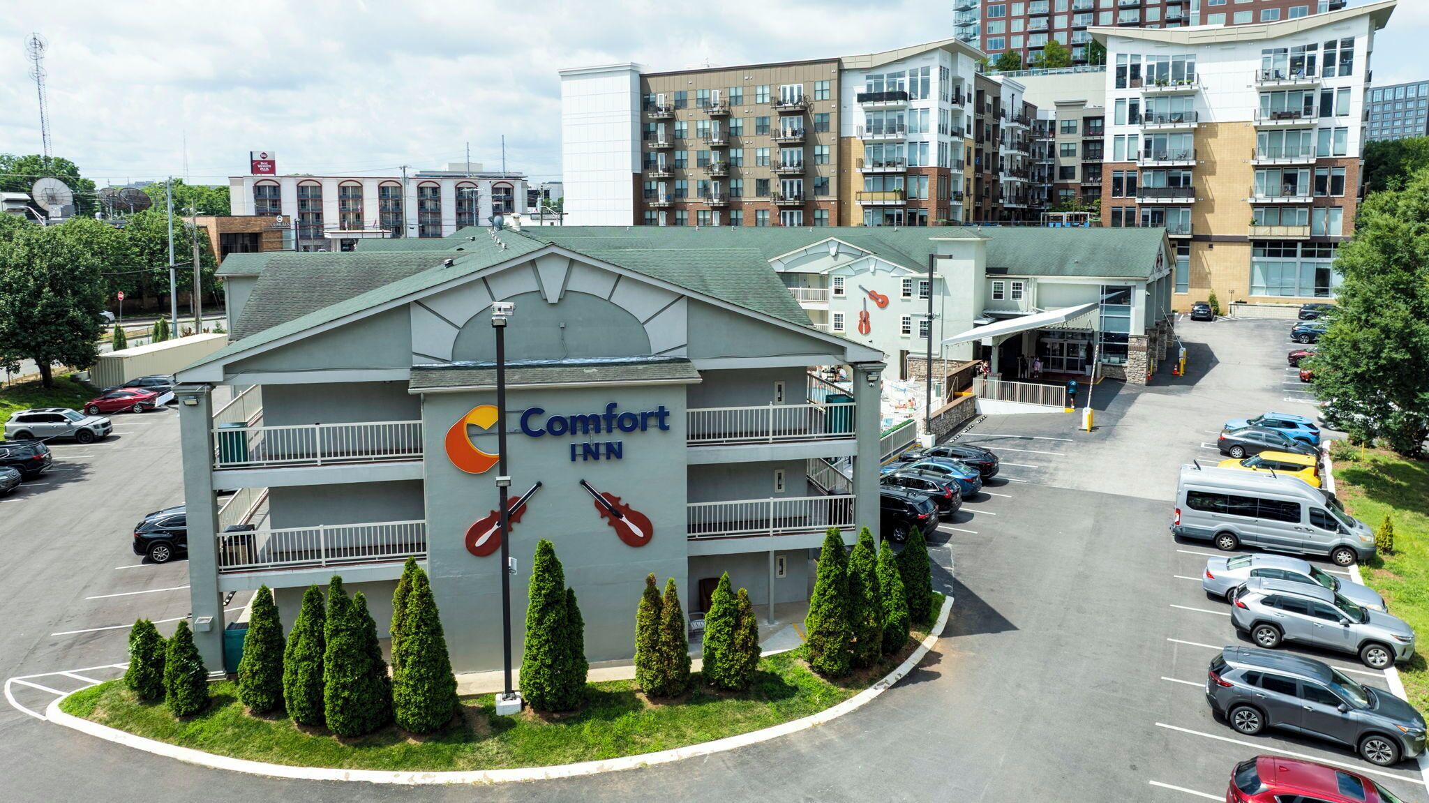 A Comfort Inn hotel with a central entrance, multiple parking spaces, and a surrounding urban environment.