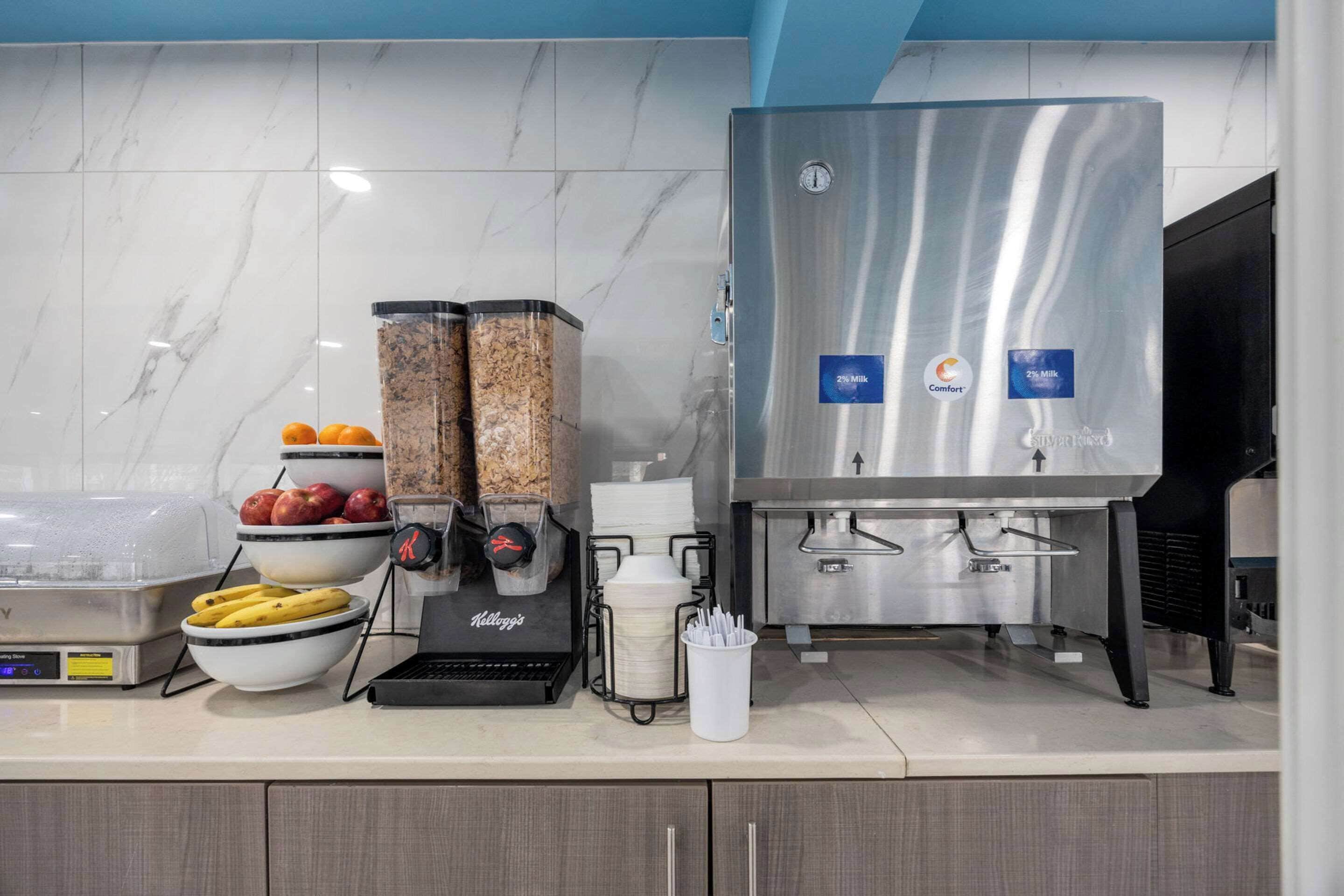 A commercial kitchen with a stainless steel beverage dispenser, a coffee machine, and various kitchen appliances.