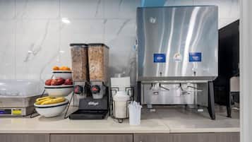 A commercial kitchen with a stainless steel beverage dispenser, a coffee machine, and various kitchen appliances.