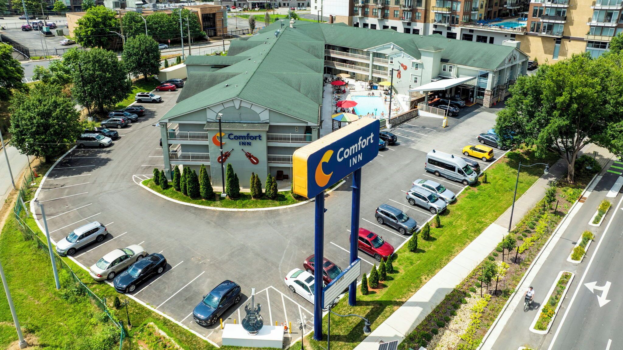 A Comfort Inn hotel with a green roof, multiple parking spaces, and a visible swimming pool area.
